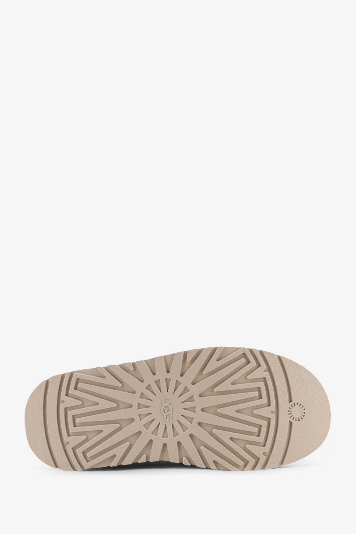 Beige rubber sole of UGG women’s Tazz suede sandals with starburst tread pattern and embossed UGG logo at center
