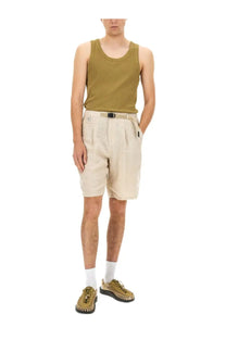 Beige undercover men’s linen shorts paired with a ribbed olive green tank top and matching woven sandals