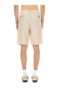 Beige undercover men’s linen shorts with relaxed fit and two back pockets shown from the back side