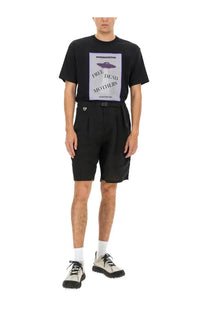 Undercover men’s linen shorts black with a black short-sleeved t-shirt featuring a purple ufo graphic and free dead mothers text