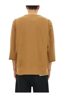A tan undercover unisex champion sweatshirt with relaxed fit three-quarter sleeves and ribbed cuffs