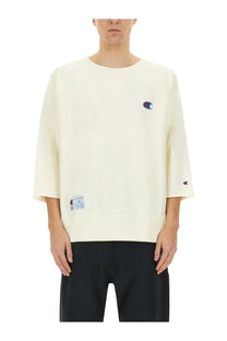 Cream-colored unisex champion sweatshirt with embroidered logo on chest and sleeve featuring relaxed fit