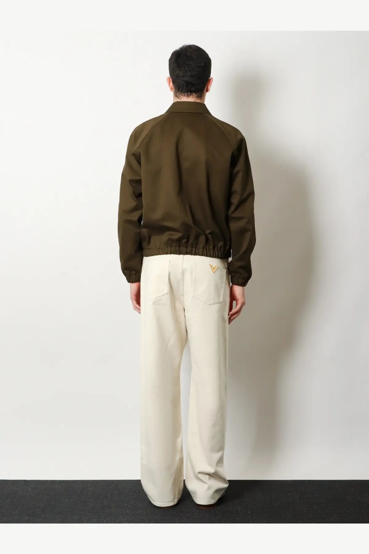 Back side of olive green valentino men’s cotton bomber jacket with subtle gold logo on back pocket