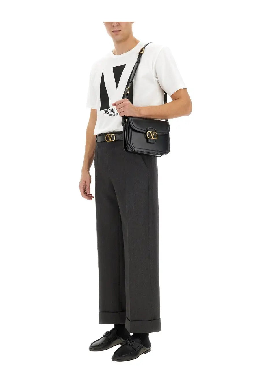 Black leather crossbody bag with gold-tone valentino logo hardware paired with valentino men’s white cotton shirt