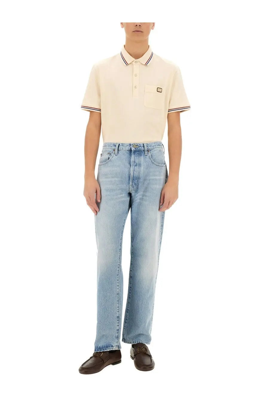 Cream-colored short-sleeved polo shirt with navy white striped collar and cuffs and black logo patch on chest pocket