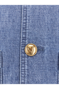 Gold-toned circular button with raised v logo on blue denim fabric of valentino men’s valentino denim sahariana jacket