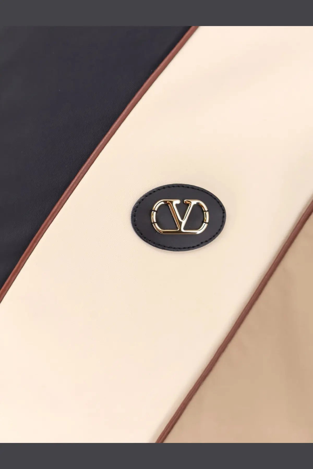Black leather patch with gold-tone interlocking v logo on cream fabric background of valentino men’s valentino jacket black