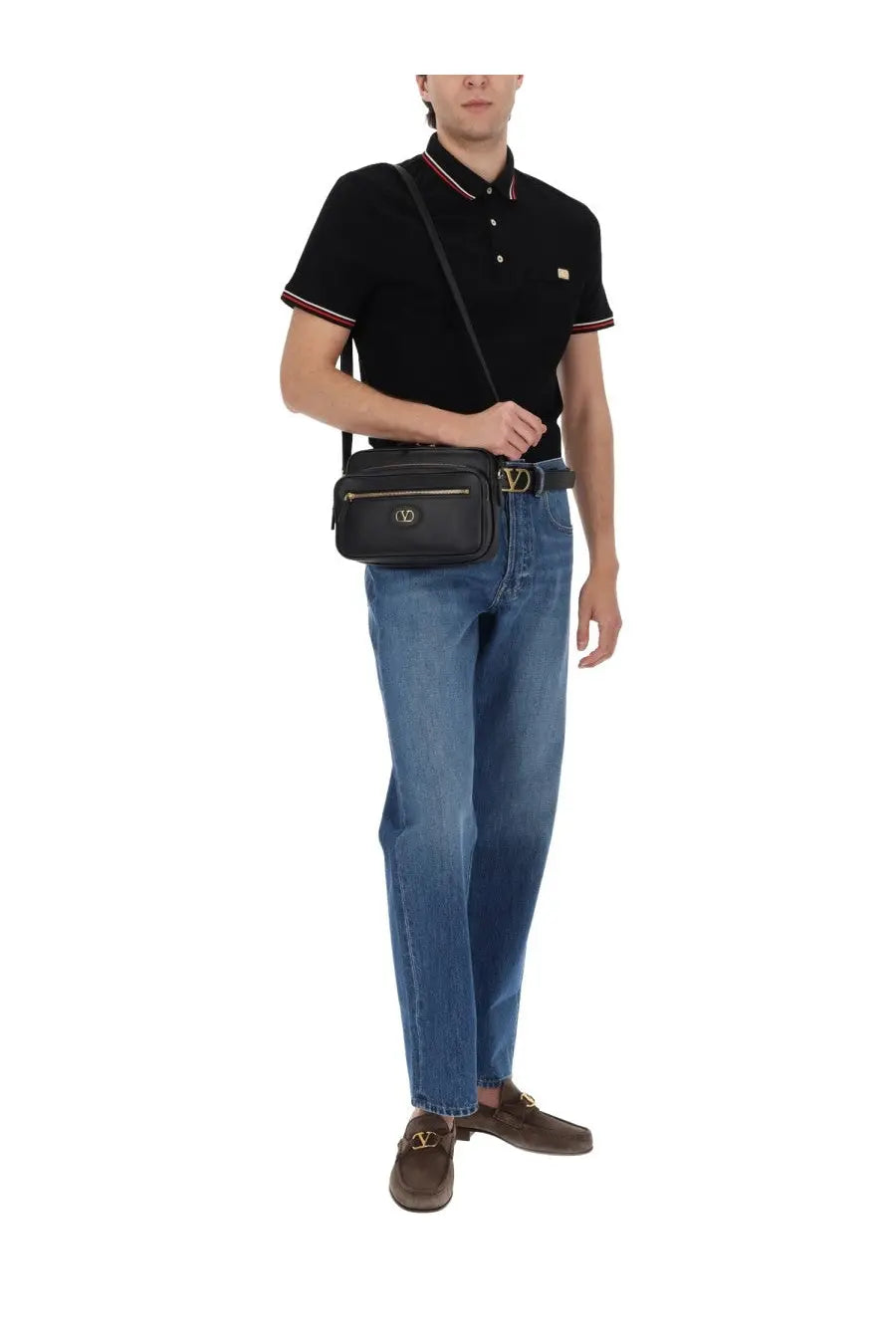 Black leather crossbody bag with gold-tone hardware and front zippered pocket paired with valentino men’s denim blue jeans