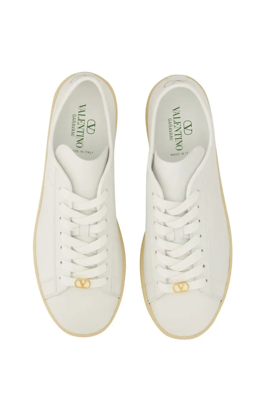 Valentino men’s white leather sneakers with gold-tone logo details and beige rubber soles visible from the back side