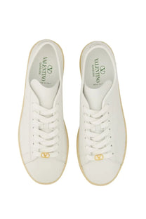 Valentino men’s white leather sneakers with gold-tone logo details and beige rubber soles visible from the back side