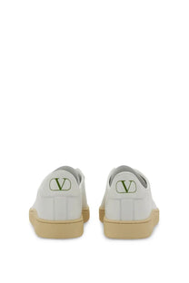 White leather Valentino men’s sneaker showing the back with green logo on heel and beige rubber soles