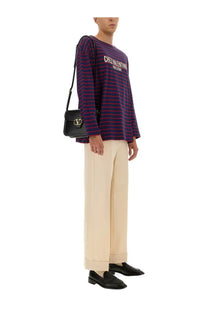 Black leather valentino handbag with gold-tone v-logo clasp paired with valentino men’s blue long sleeve shirt