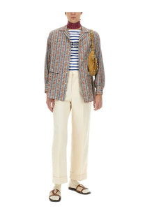 A tan leather crossbody bag with gold-tone hardware and textured surface paired with Valentino men’s multicolor pajama shirt