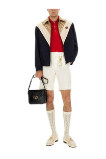 Black leather handbag with gold-tone valentino logo clasp shown alongside red valentino men’s polo shirt