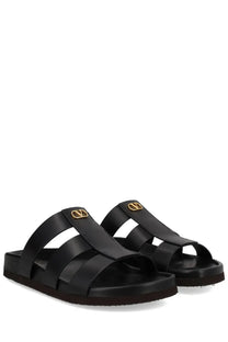 Black leather Valentino men’s sandalo slide sandals with gold-tone logo hardware and studshield design