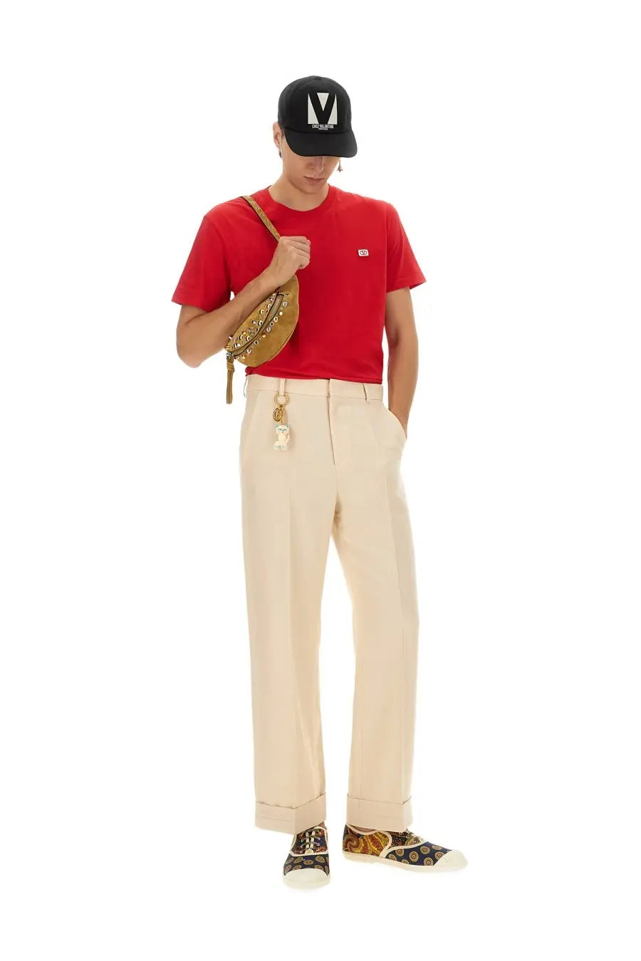 A tan leather crossbody bag with gold-tone hardware and chain strap shown alongside a Valentino men’s red shirt
