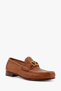 Tan leather valentino men’s vlo logo loafer featuring gold tone logo buckle on the front