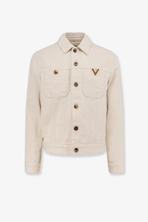 Valentino men’s white denim jacket featuring gold-tone buttons and a triangular logo on the left chest pocket