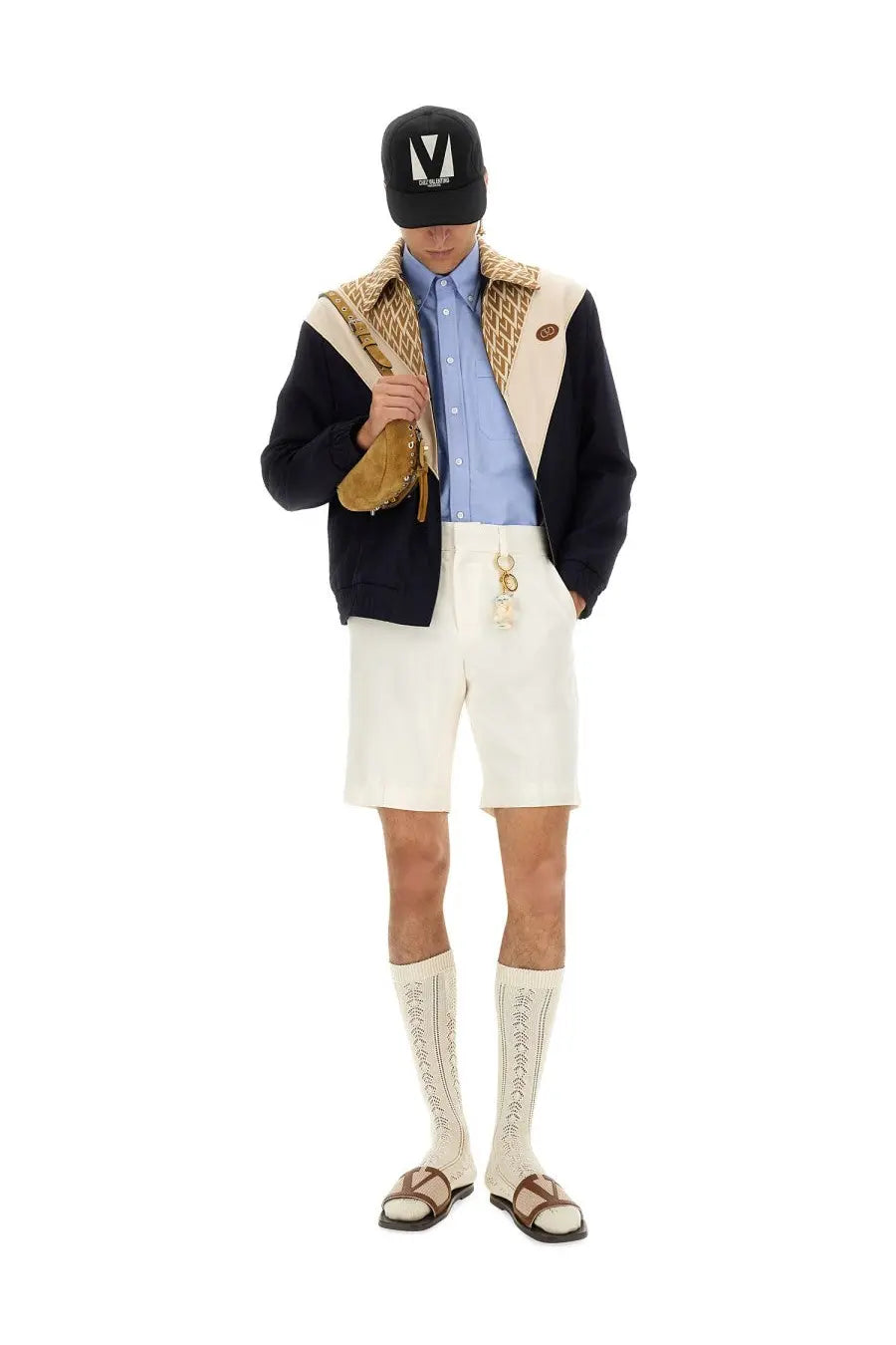 A tan leather crossbody bag with gold-tone metal clasp and chain strap paired with valentino men’s multicolor wool bomber jacket
