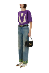 Black leather Valentino handbag with gold-tone logo clasp paired with purple chez Valentino print shirt for women