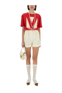 White leather handbag with gold-tone hardware and distinctive logo clasp paired with valentino red print shirt
