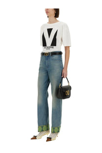Black leather Valentino handbag with gold-tone logo hardware paired with Valentino women’s white Chez Valentino print shirt