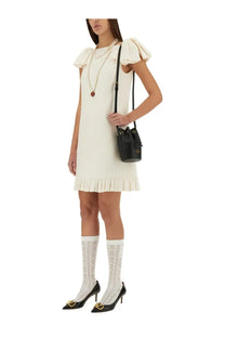 Valentino women’s white crepe couture short dress paired with black leather gucci bucket bag with gold hardware and drawstring closure