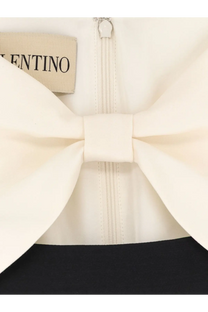 Cream-colored satin bow with a ribbed valentino label and silver zipper on valentino women’s black crêpe midi dress
