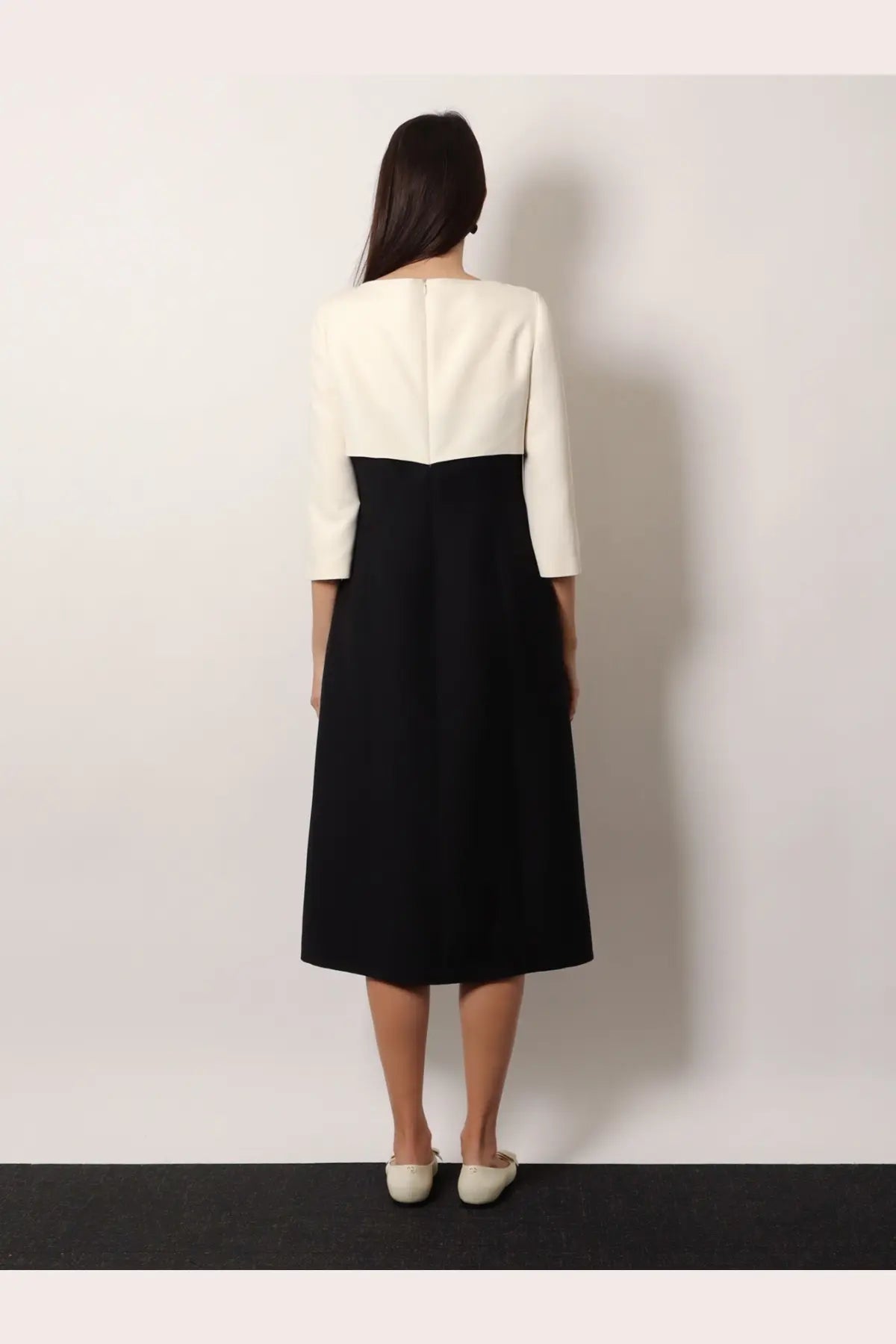 A woman wears a Valentino women’s crêpe midi dress black with a structured cream bodice and flowing black skirt