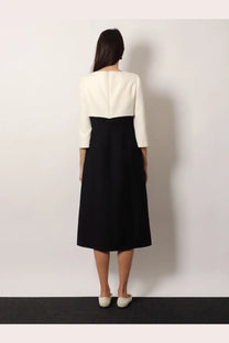 A woman wears a Valentino women’s crêpe midi dress black with a structured cream bodice and flowing black skirt