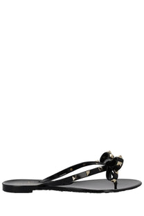 Valentino women’s black glossy flip-flop sandal with a bow adorned by gold-tone triangular studs