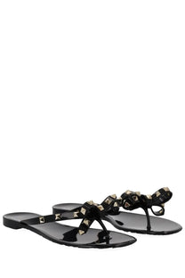 Valentino women’s black glossy patent leather thong sandals with gold-tone pyramid studs and decorative bow