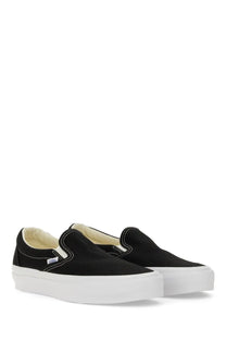 Vans unisex slip on premium sneaker in black canvas with white rubber sole and small Vans logo on the side