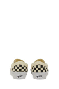 Cream-colored Vans unisex slip-on premium white sneakers with black and white checkerboard pattern on the heel back side