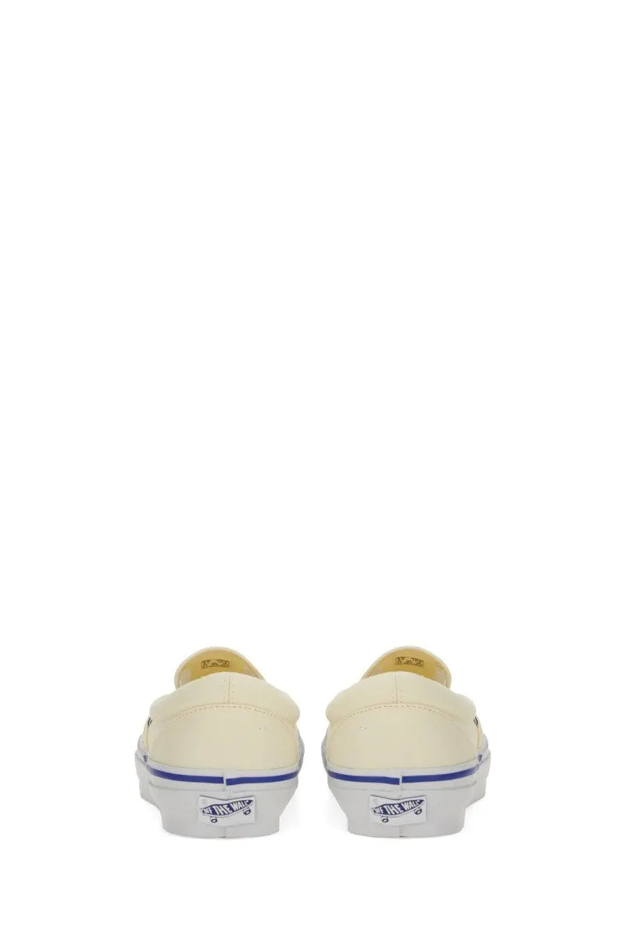 Back view of cream-colored canvas vans unisex slip-on sneaker with blue stripe and white rubber outsole showing vans logo