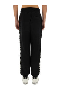 Black Versace Jeans Couture men’s jogging pants featuring white vertical lettering along the outer leg