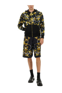 Versace jeans couture men’s black shorts paired with a black and gold ornate baroque-patterned hoodie