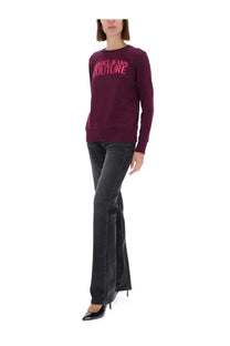 A maroon long-sleeved sweatshirt with versace jeans couture printed in pink across the chest for women