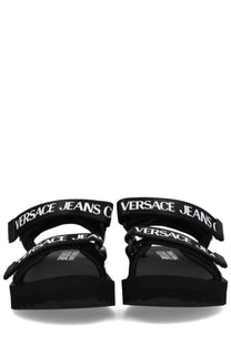 Versace Jeans Couture women’s black sandal with bold white logo straps and chunky platform sole