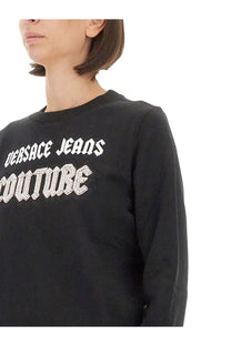 Black versace jeans couture women’s sweatshirt with long sleeves featuring white lettering and rhinestone embellishments