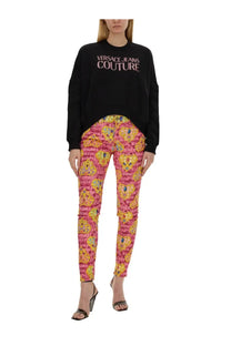 Pink and yellow patterned versace jeans couture pants with bold repeating lion motif paired with black sweatshirt