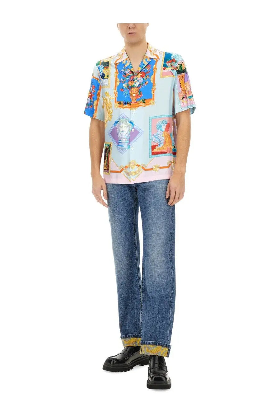 Versace men’s short-sleeved shirt with colorful collage print in blue pink gold and white paired with denim jeans