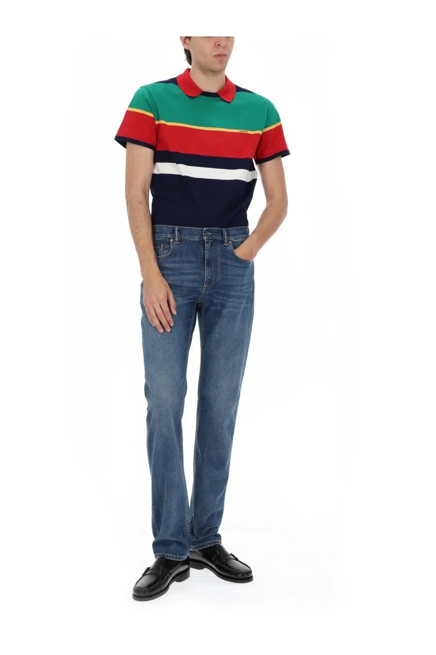 A man wearing a colorful striped polo shirt with red green navy blue and white bands paired with versace denim jeans