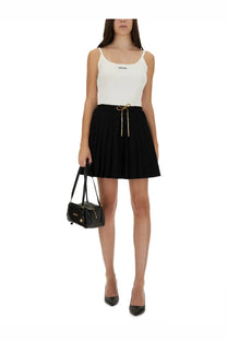 Versace women’s black cotton skirt paired with black leather mini bag featuring gold hardware and front zip closure