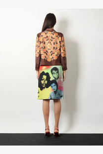 A woman wears a versace women’s informal silk brown blouse with orange circular patterns and a matching pop-art skirt