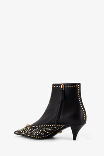 Versace women’s black leather ankle boots with gold-tone studs and a small golden logo at the toe