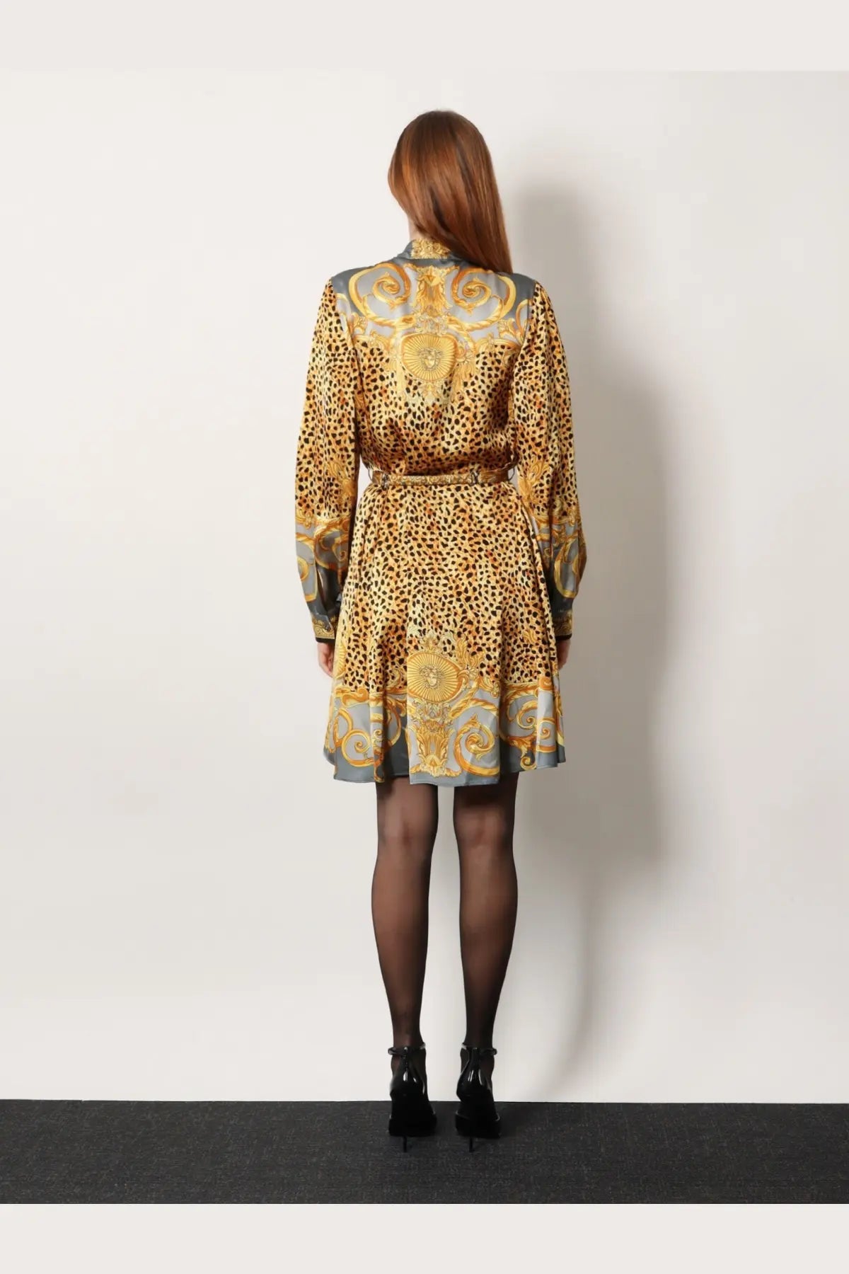 A woman wearing a versace women’s silk chemisier dress in grey with bold leopard print and gold ornate baroque patterns