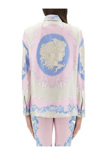 A woman wearing a Versace women’s silk shirt cameo blue with elegant pink and blue classical portrait print