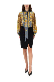 A woman wearing a versace women’s silk shirt grey with bold leopard print and gold baroque pattern paired with black trousers