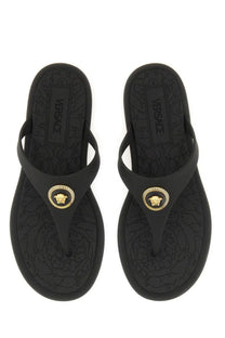Versace women’s black rubber thong sandal with gold medusa head emblem and embossed floral sole pattern